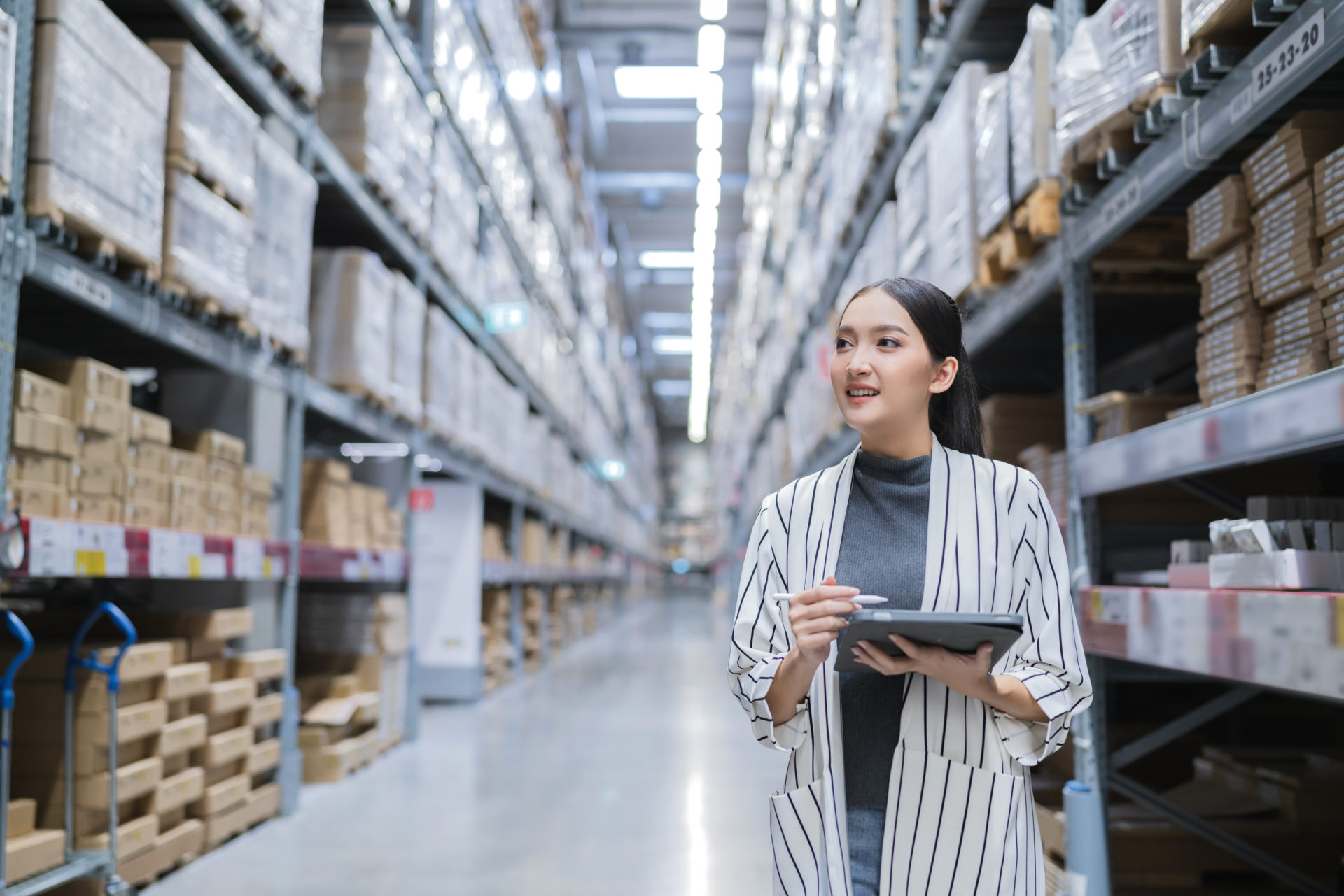 Portrait of asian woman business owner using digital tablet checking amount of stock product inventory on shelf at distribution warehouse factory.logistic business shipping and delivery service